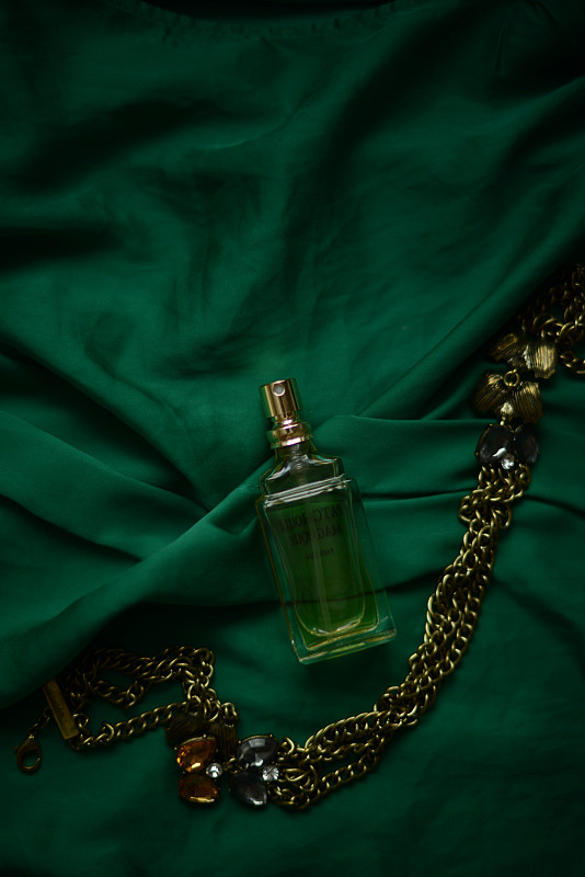绿色背景上的香水瓶和项链图片下载