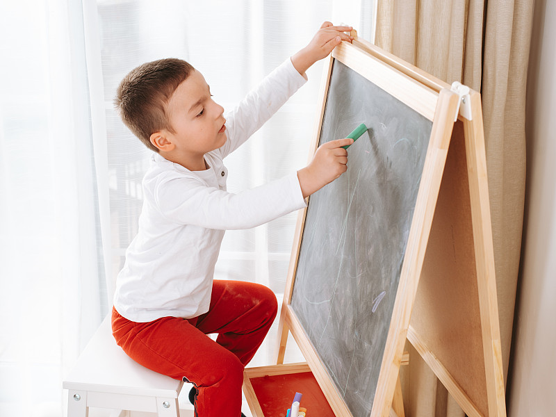 小男孩在黑板上画画图片素材