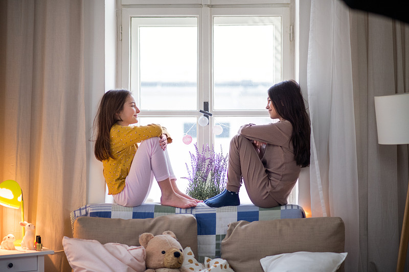 侧面是两个小女孩坐在窗台上聊天。图片下载