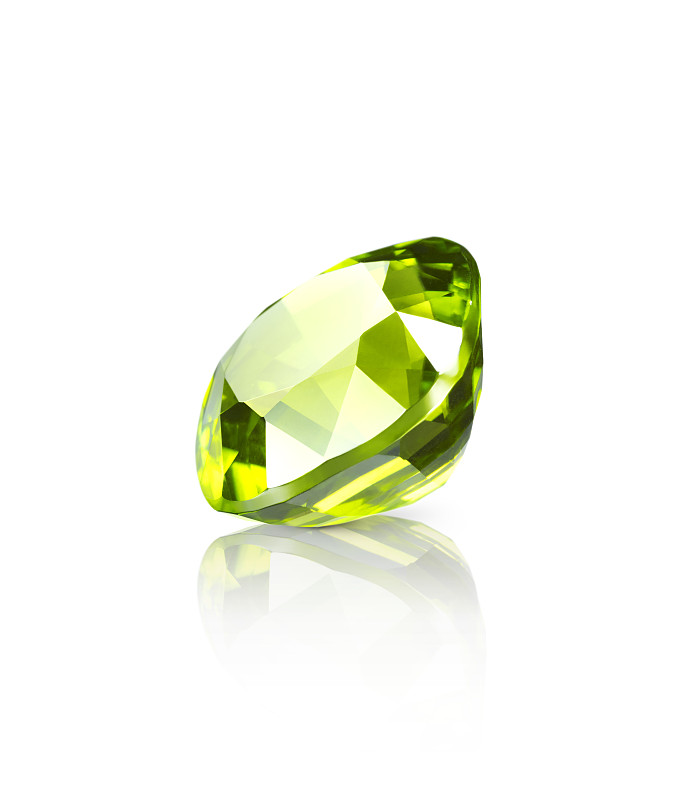 闪光的浅绿色橄榄石宝石躺在一个白色的表面上的一个下降的阴影和反射的近对角线视图图片下载