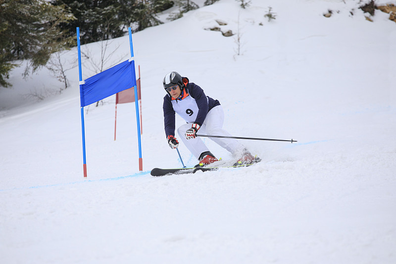 业余冬季运动高山滑雪大回转比赛。老年男子在滑雪场滑雪。高山雪景图片下载