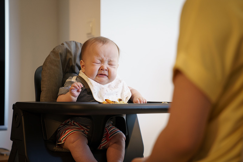 婴儿在她的高椅子上打喷嚏图片素材