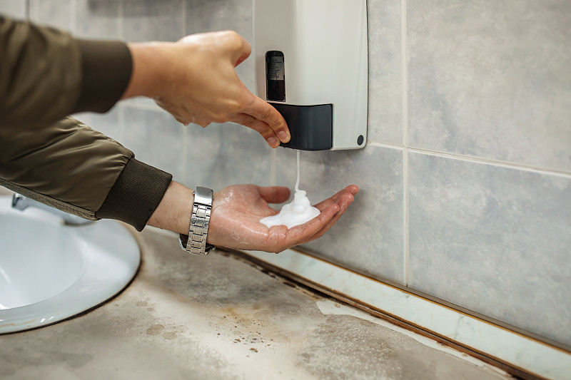 戴口罩的男子在公共厕所洗手图片下载