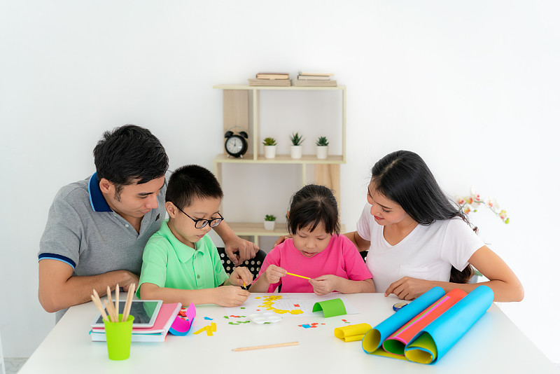 亚洲家庭与父亲，母亲，女儿和儿子编辑彩色纸制作艺术品，并参与手工艺项目和奖励活动在家自学。图片素材