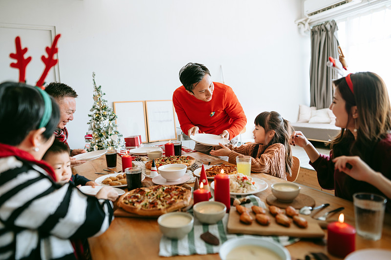 快乐的亚洲多代家庭一起庆祝圣诞节，在圣诞节聚会期间在家里传递和分享食物图片下载