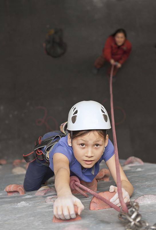 在英国，一个小女孩在爬室内攀岩墙图片素材