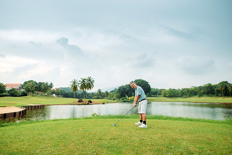亚洲华人活跃的资深男高尔夫球手在高尔夫球场上打高尔夫球图片下载