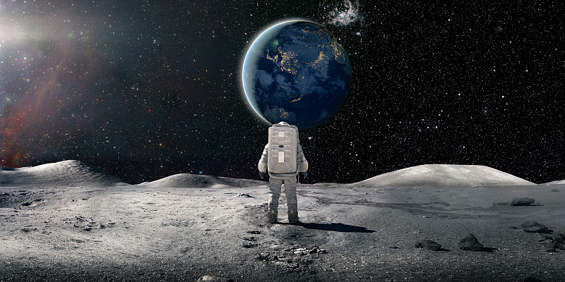 孤独的宇航员穿着宇航服站在月球上看着遥远的地球图片下载