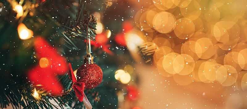 人造圣诞树的树枝上有红色的装饰物和花环在闪亮的背景上图片下载