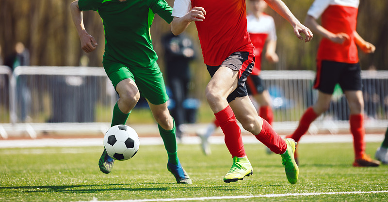 足球运动员在决斗中奔跑。成人足球运动员在比赛中。运动员在草地上踢足球图片下载