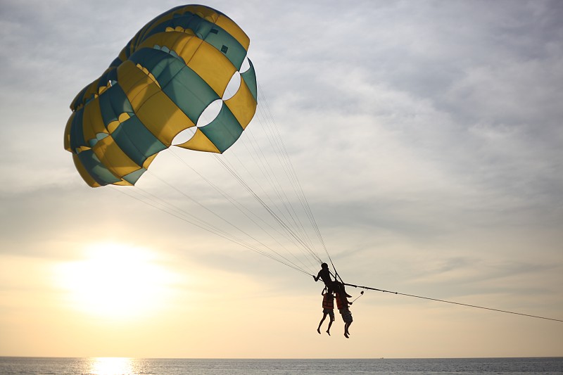 从低角度看，人在海上滑翔伞对抗天空摄影图片