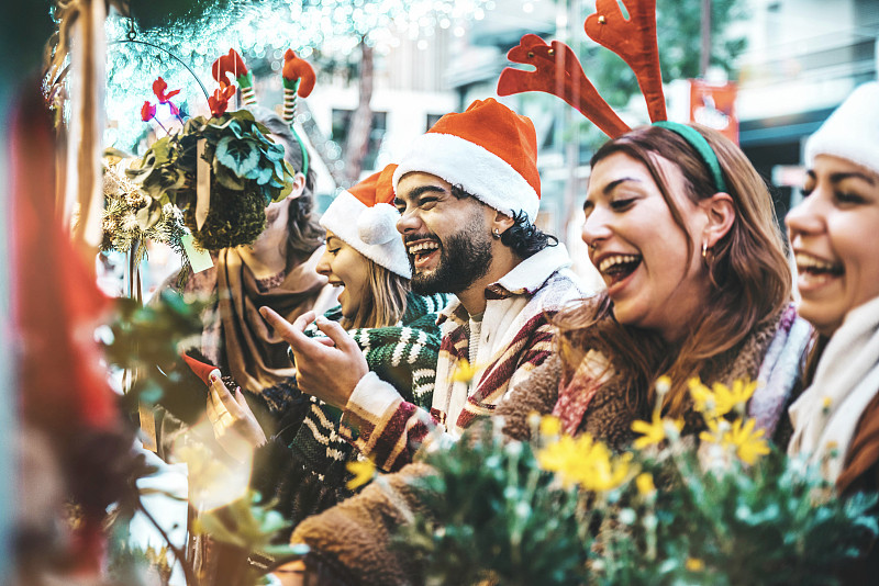 一群快乐的朋友在圣诞市场纪念品店玩耍-快乐的年轻游客在外面享受寒假-传统文化和假期概念图片下载