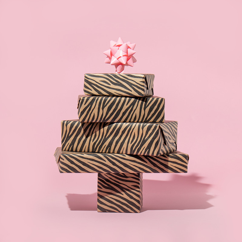 圣诞创意布局与礼品形成圣诞树在柔和的粉红色背景。八九十年代的审美时尚假日概念。迷你新年派对的想法。图片下载