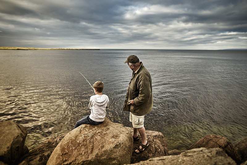 英国，苏格兰，男孩和老人一起钓鱼图片素材