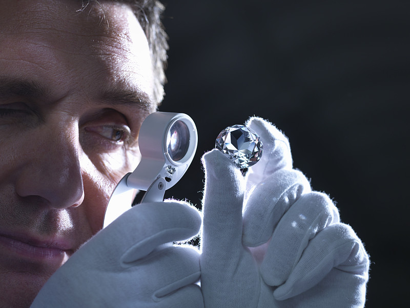 Jeweller inspecting replica diamonds with loupe图片素材