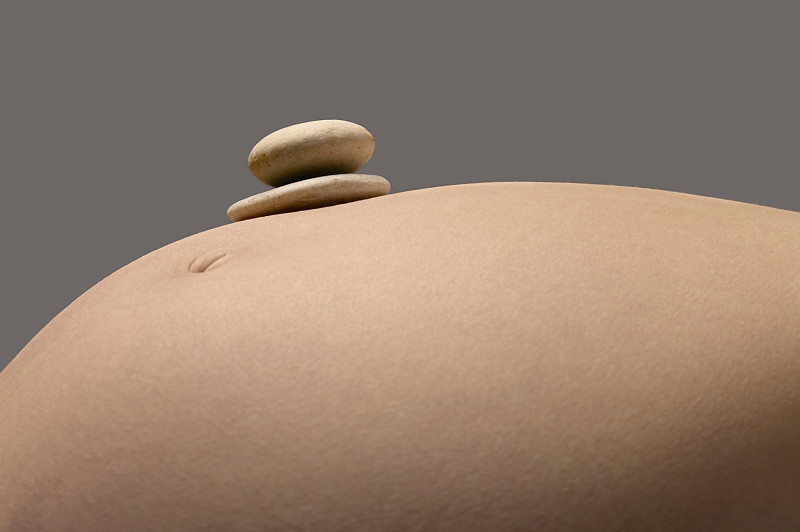 一个孕妇的胃的特写，上面有两个鹅卵石图片素材