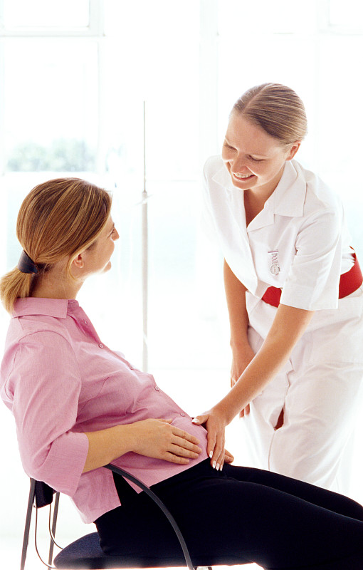 一个年轻的女护士感觉一个孕妇的胃图片下载