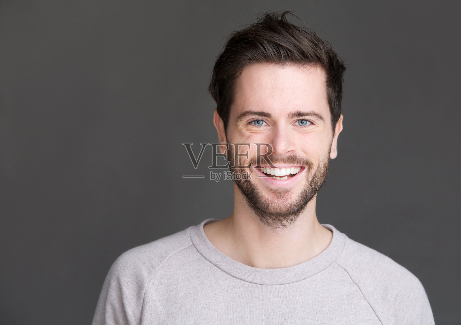 一个快乐的年轻人在灰色的背景微笑的肖像照片摄影图片