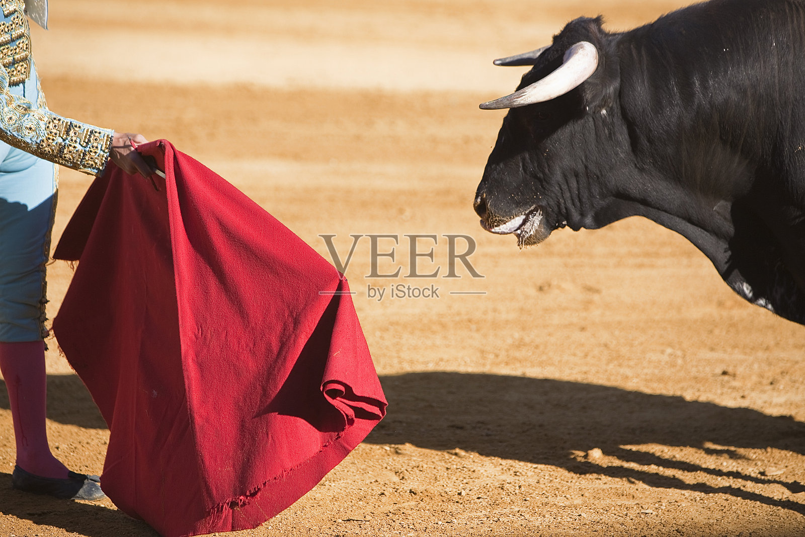 在西班牙斗牛中，斗牛士向公牛挥舞着红色斗篷照片摄影图片