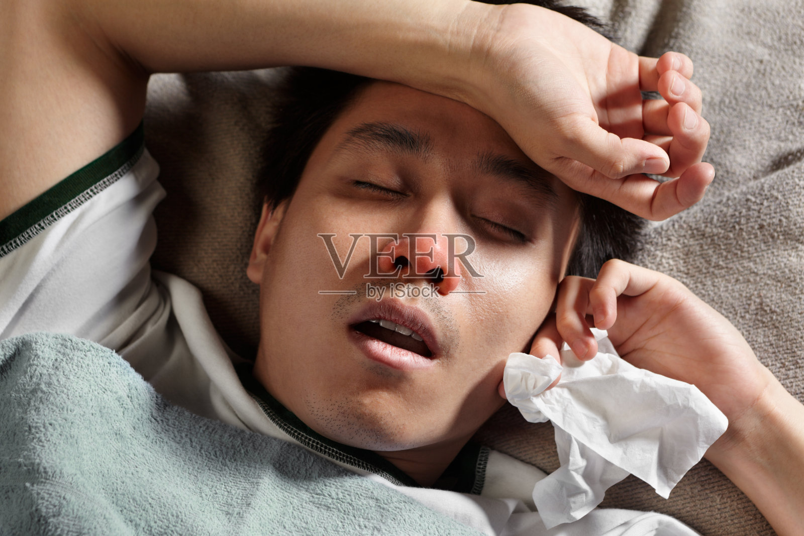 一个生病的年轻人拿着一张纸巾躺着照片摄影图片