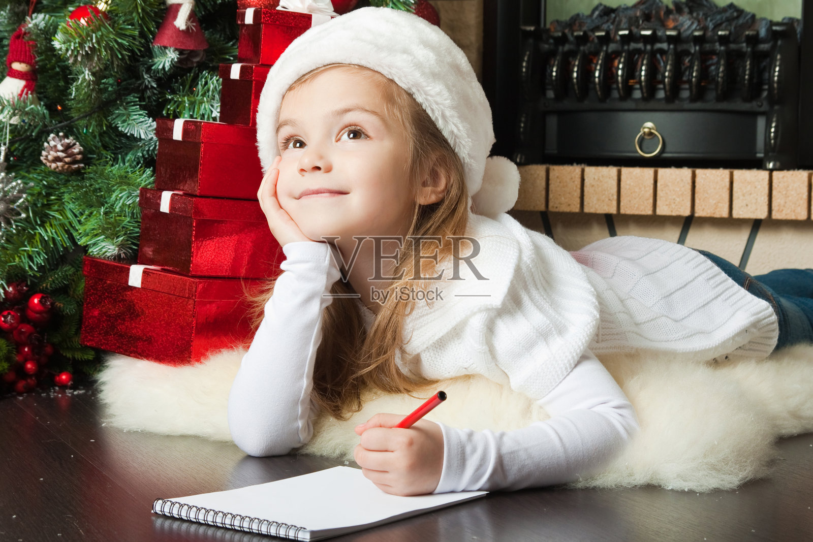 漂亮的女孩戴着圣诞老人的帽子写信照片摄影图片
