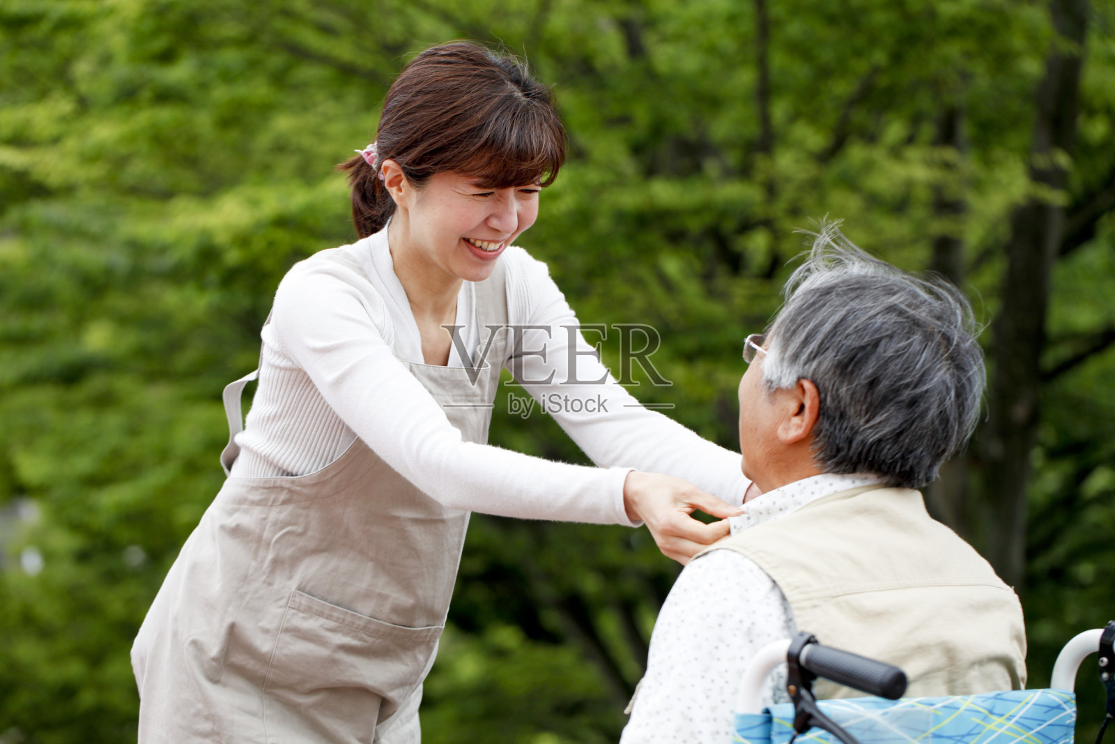 一位妇女在帮助一位坐轮椅的老人照片摄影图片