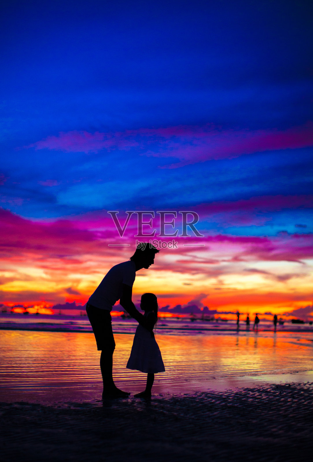 父亲和女儿的剪影在日落的海滩上照片摄影图片