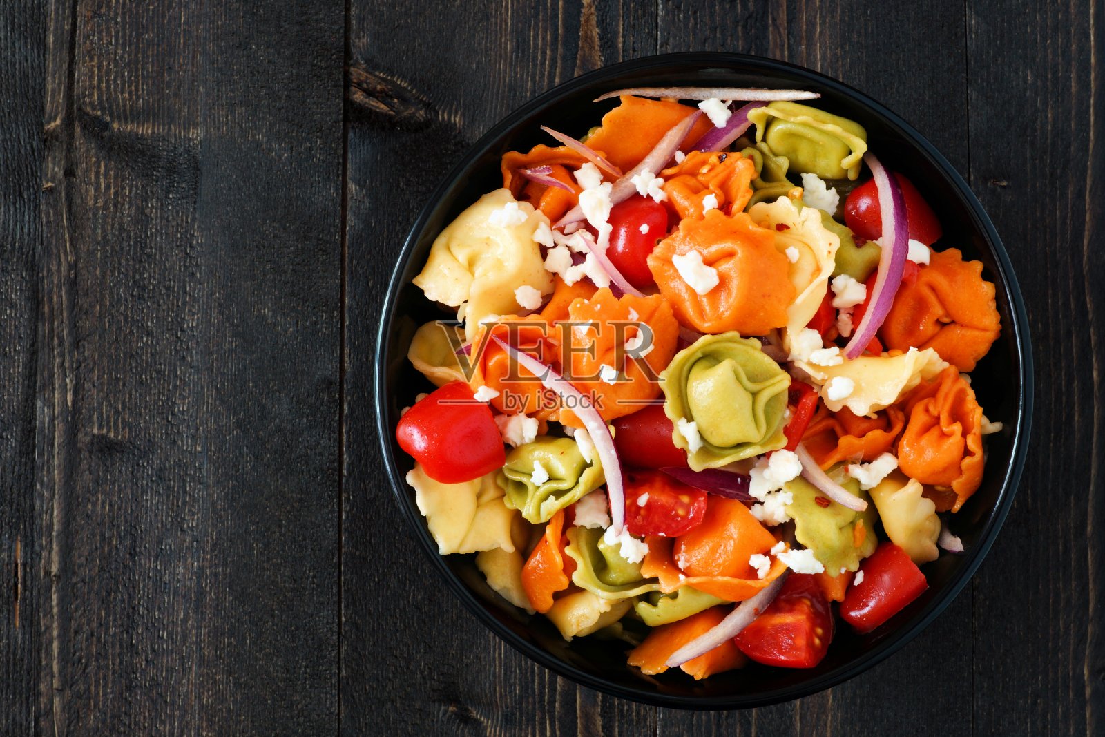 色彩斑斓的意大利饺子沙拉，俯视深色木材照片摄影图片