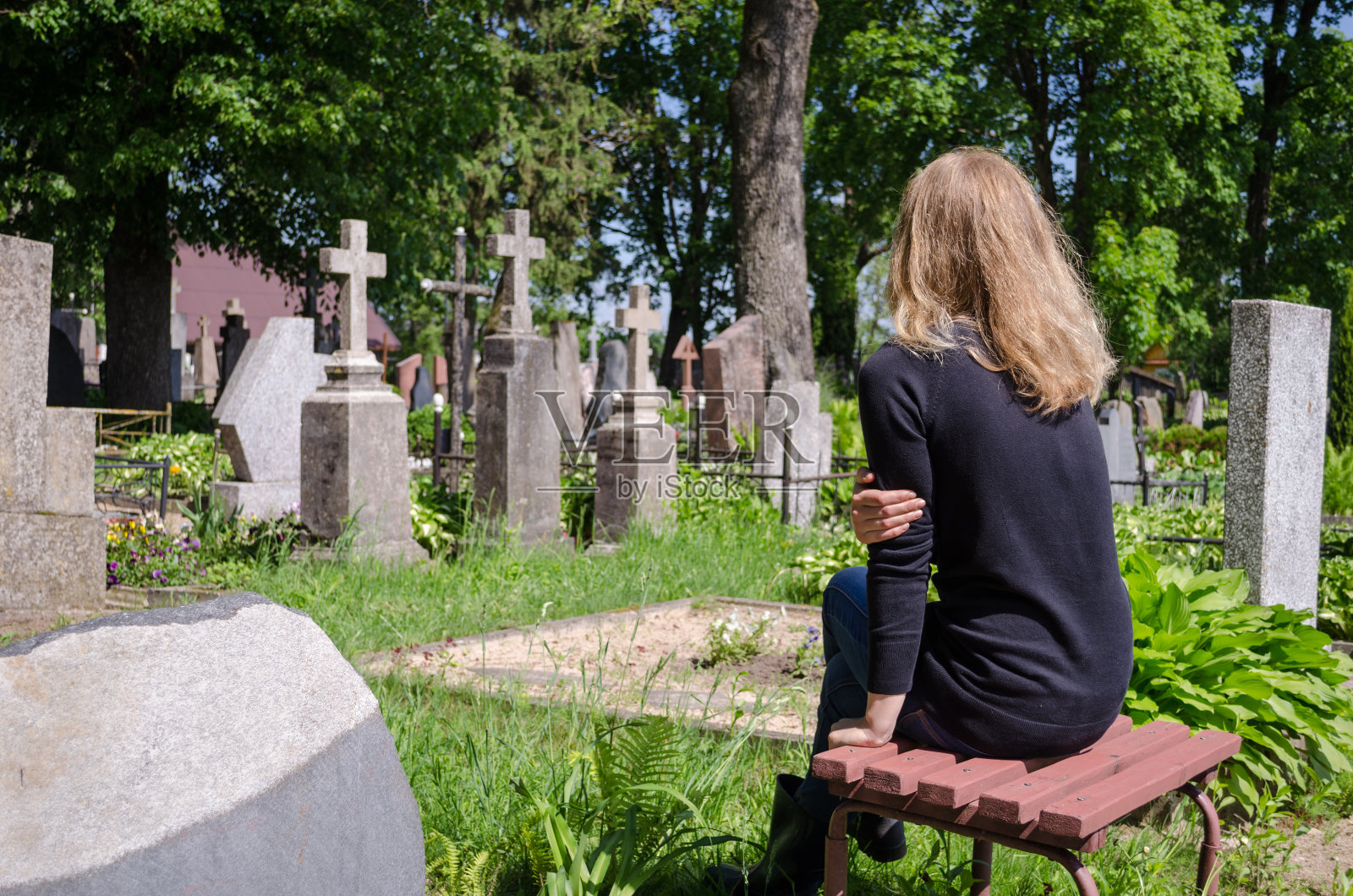悲伤的女人靠近父亲的丈夫墓在墓地里照片摄影图片