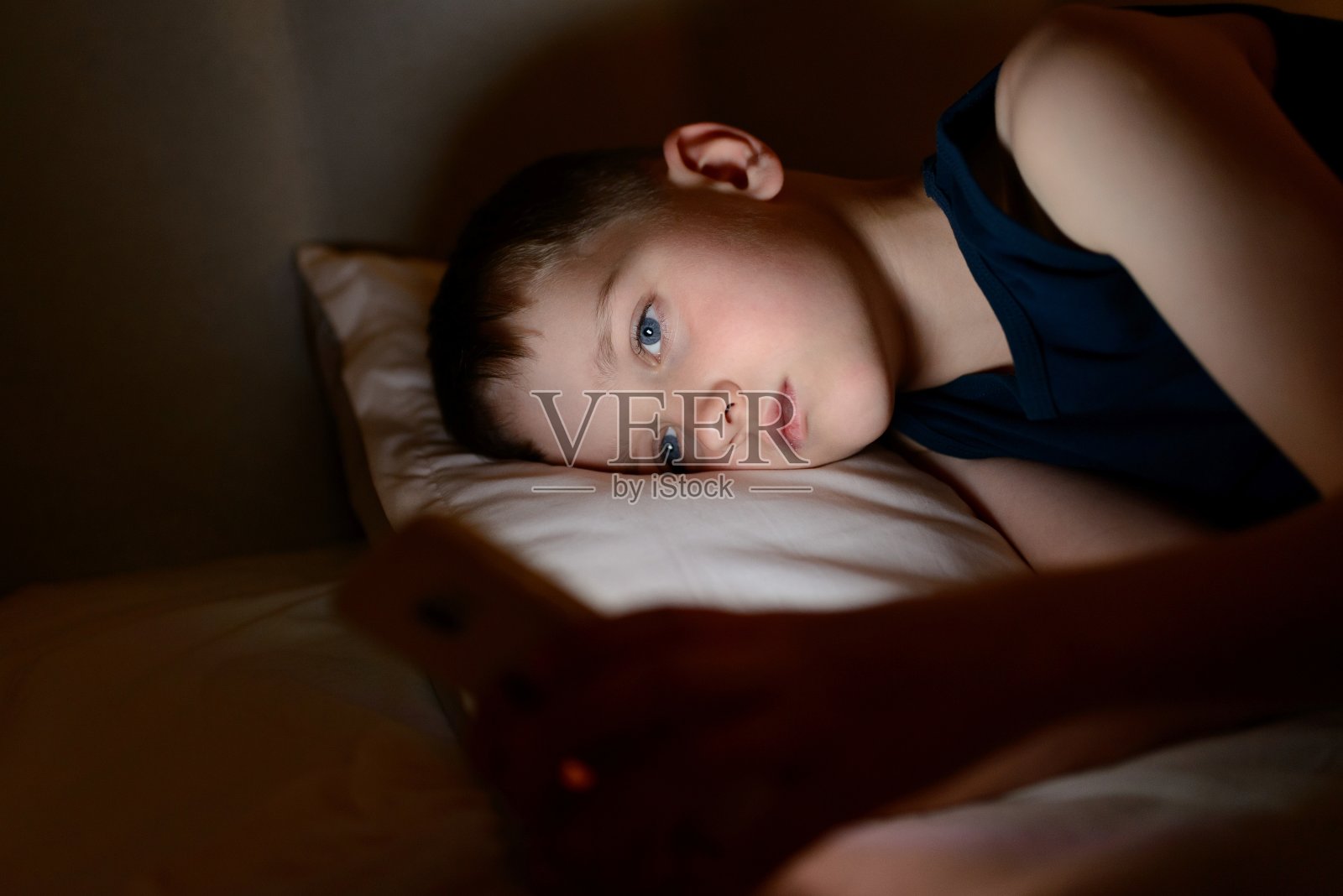 7岁的男孩在晚上使用智能手机照片摄影图片