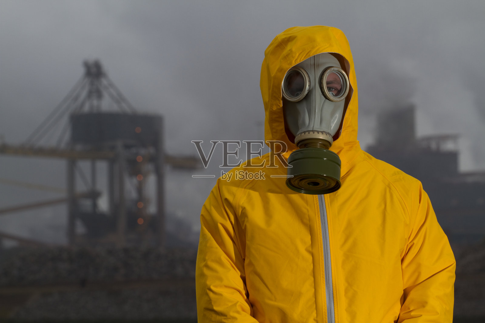 一名戴着防毒面具的男子站在工厂前。额。照片摄影图片