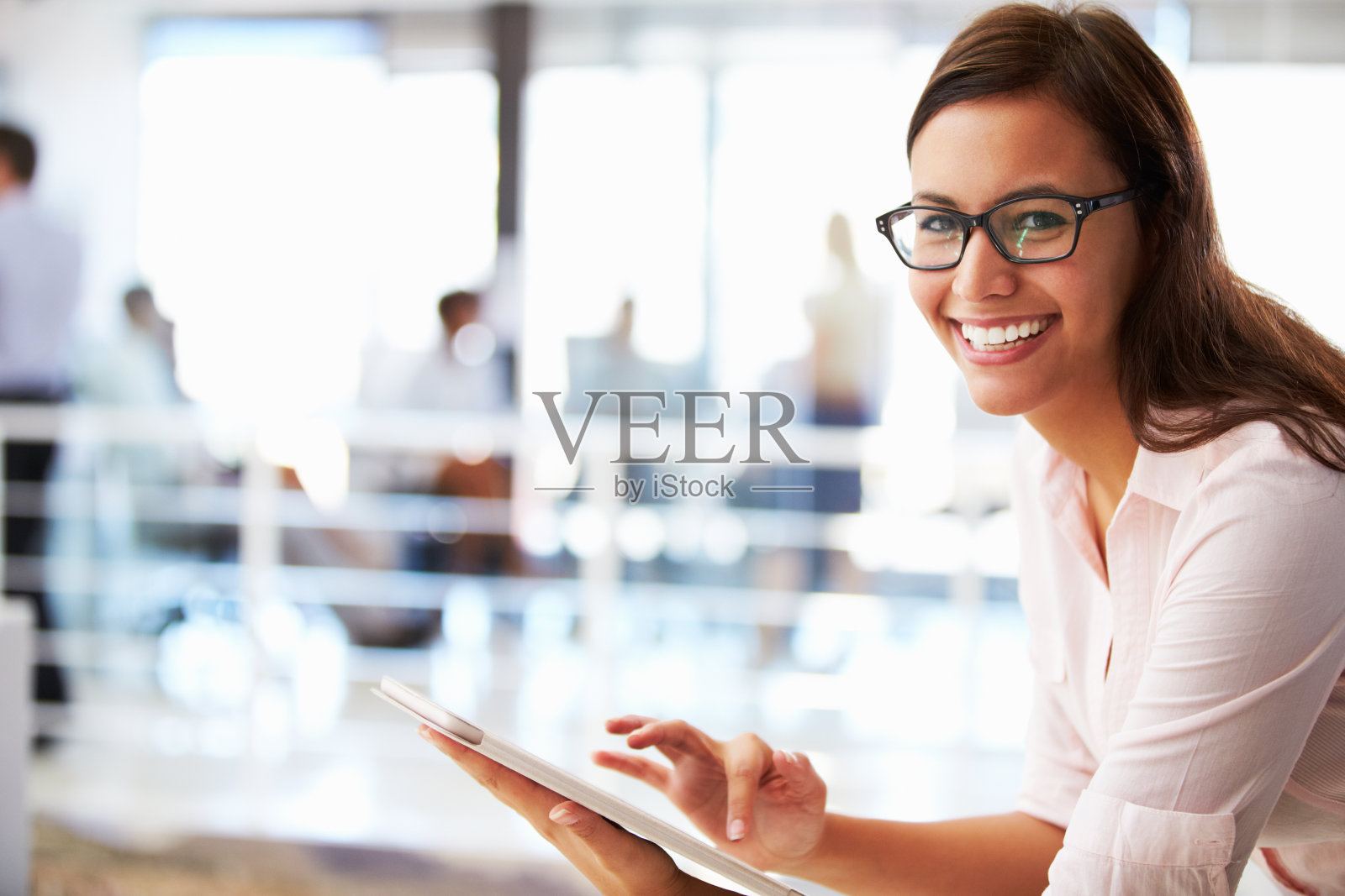 在开放式办公环境中使用平板电脑的微笑女人照片摄影图片