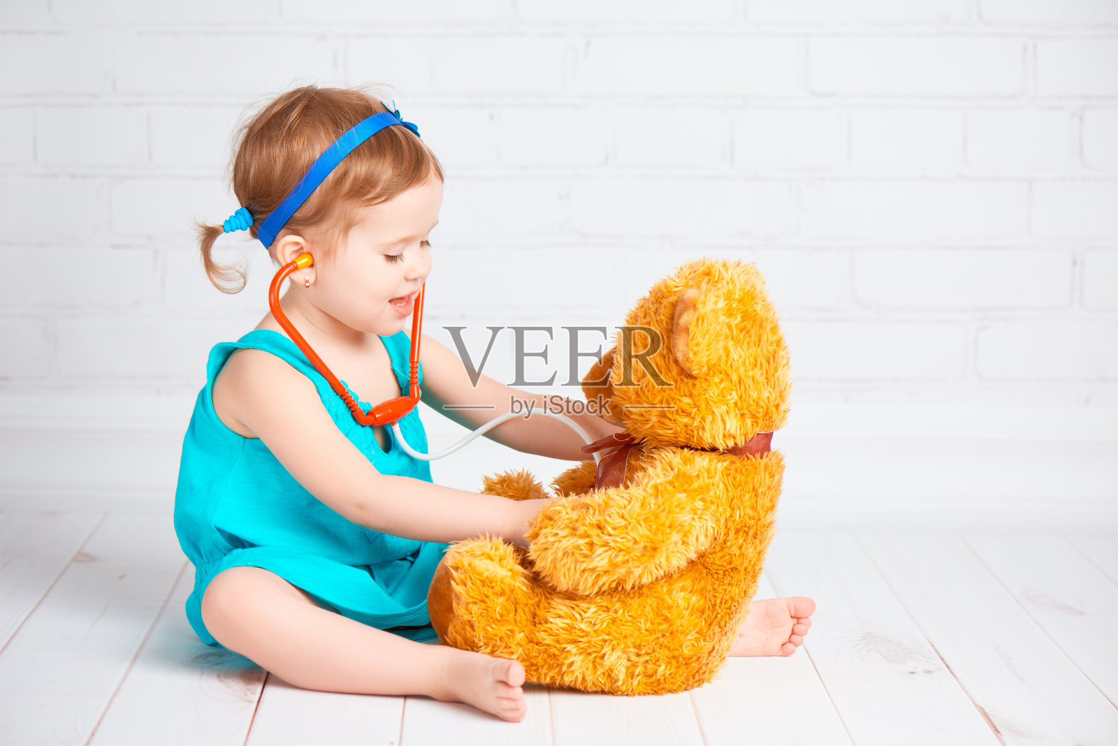 女孩扮演医生和治疗泰迪熊照片摄影图片