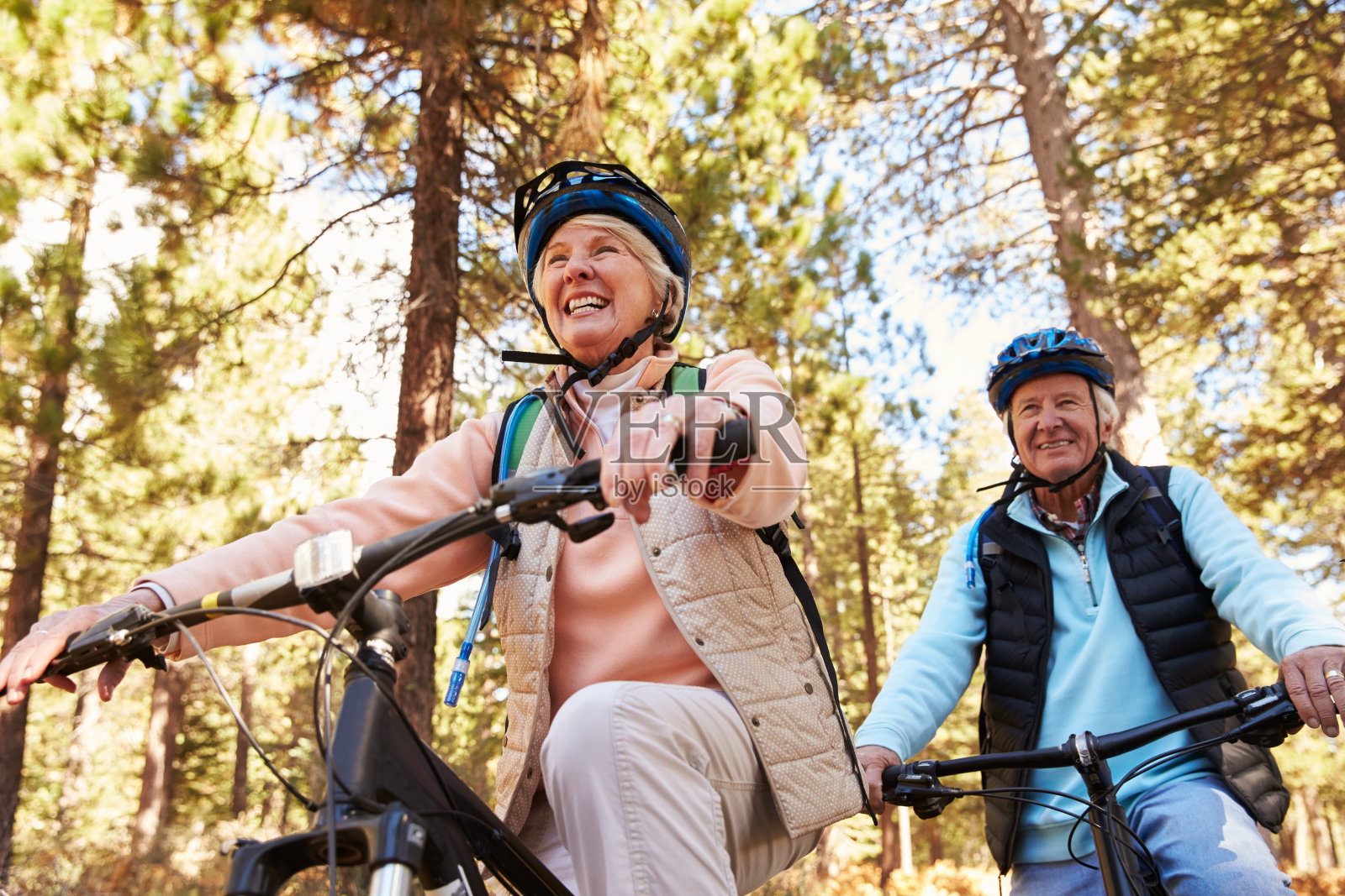 一对老年夫妇在森林小径上骑山地自行车，低角度照片摄影图片