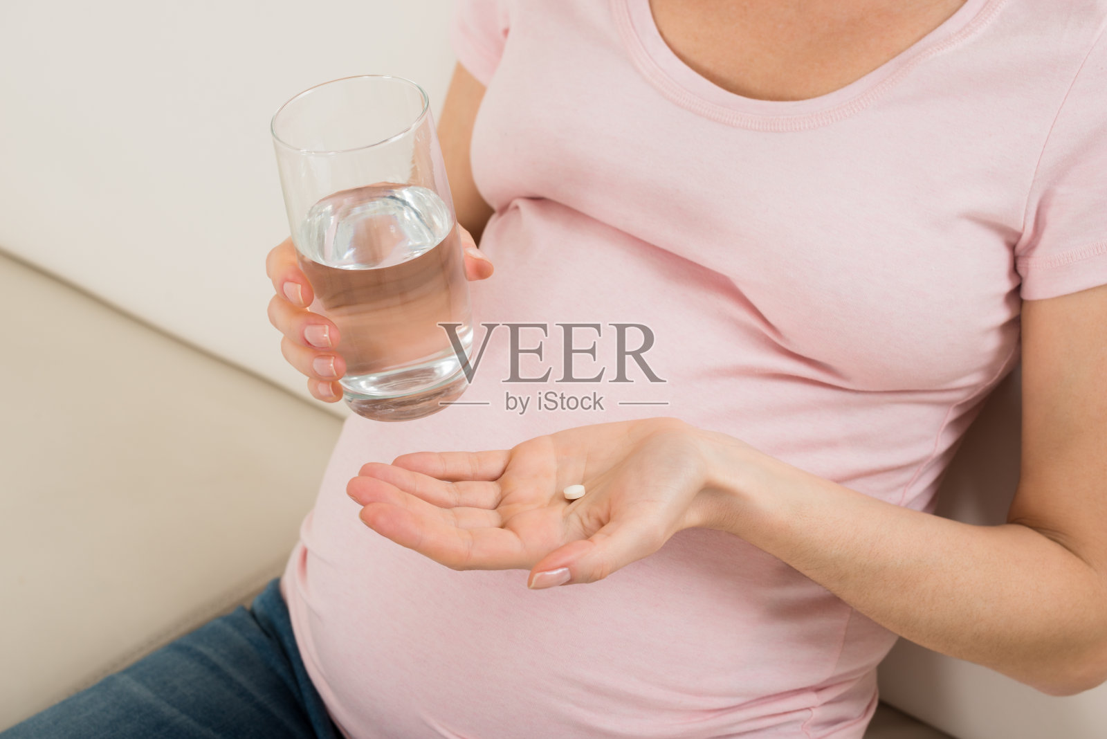 孕妇手里拿着一杯水和维生素片照片摄影图片