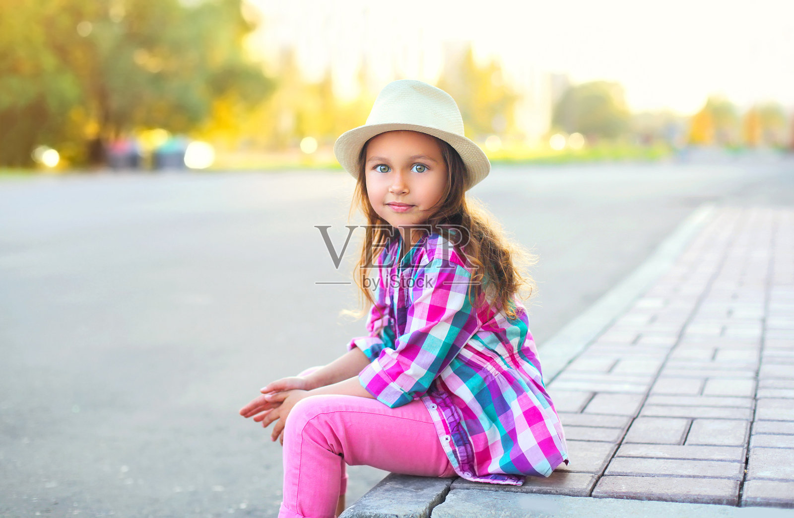 漂亮的小女孩穿着衬衫和帽子在城市里照片摄影图片