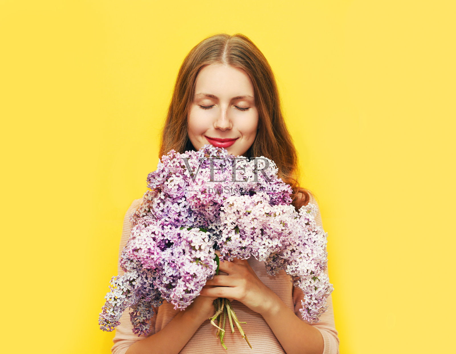 快乐微笑的女人享受着淡紫色的花香越过黄色照片摄影图片