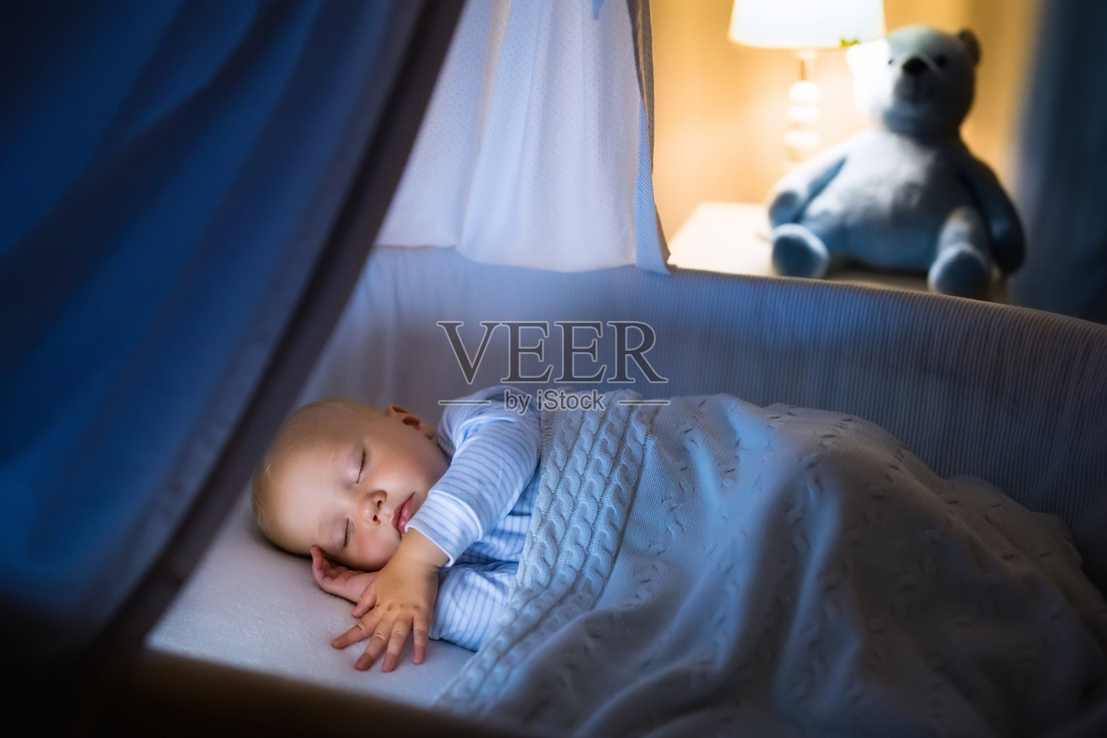 小男孩晚上睡在蓝色的摇篮里照片摄影图片