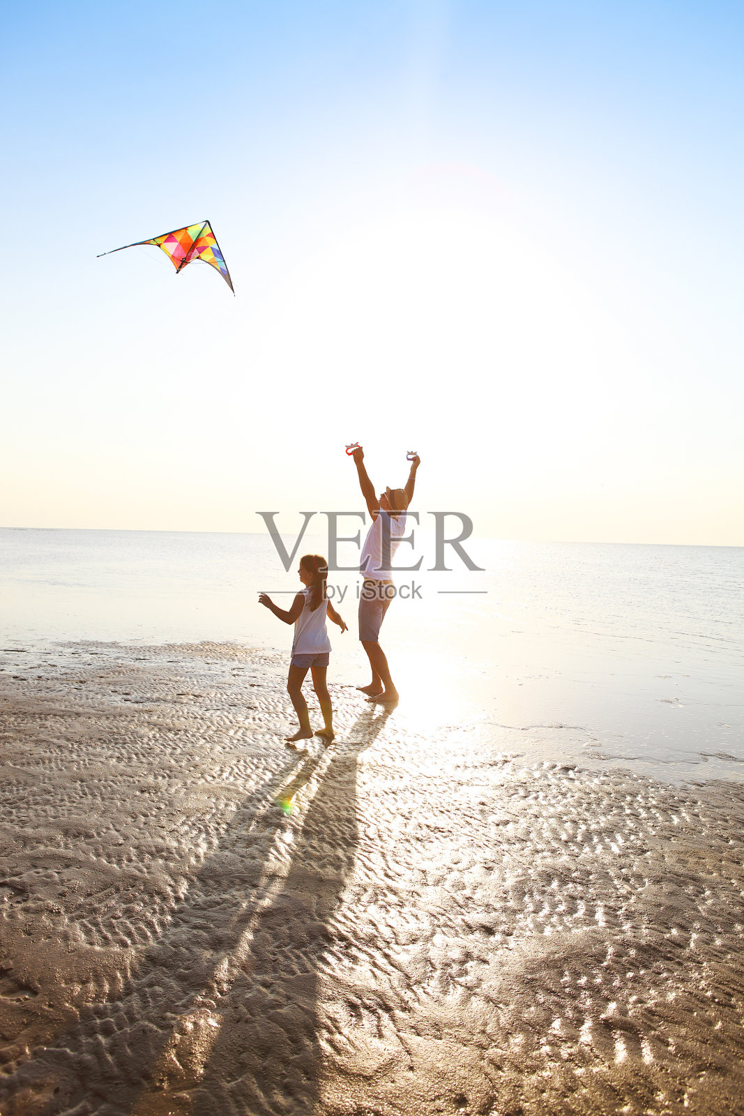 快乐的年轻父亲与女儿和在海滩上放风筝照片摄影图片