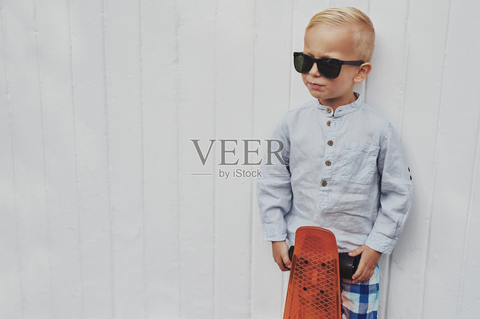 严肃时髦的小男孩摆着滑板的姿势照片摄影图片