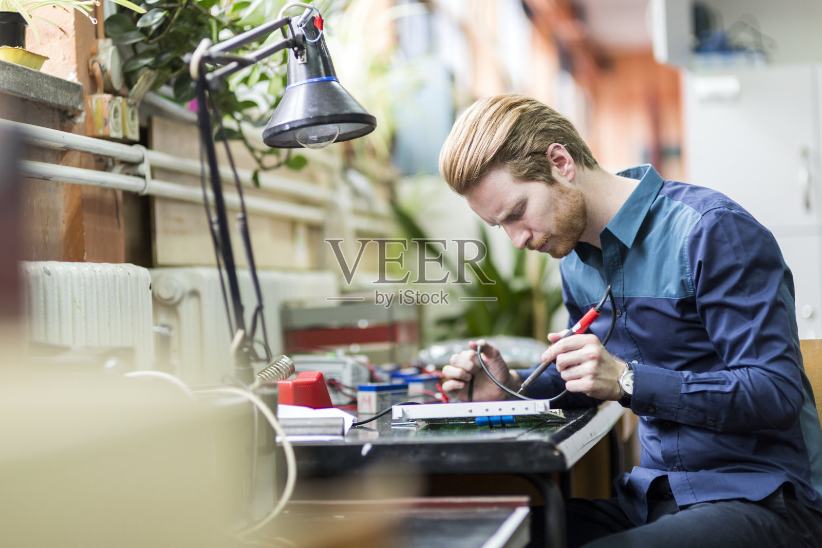 年轻英俊的男子正在焊接电路板照片摄影图片