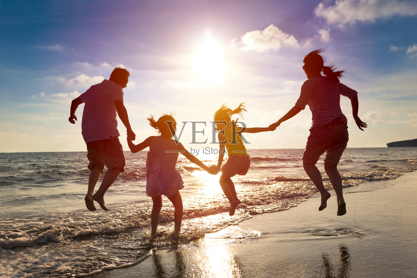 快乐的一家人一起在海滩上跳跃照片摄影图片