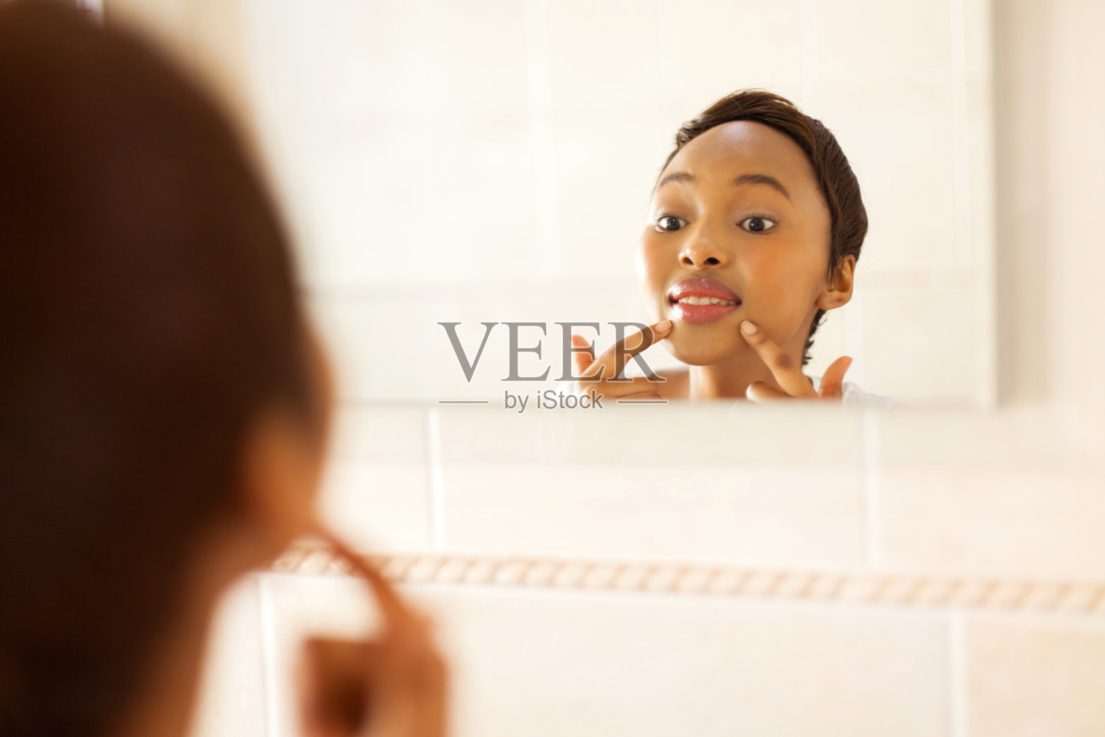 年轻的非洲妇女检查她脸上的青春痘照片摄影图片
