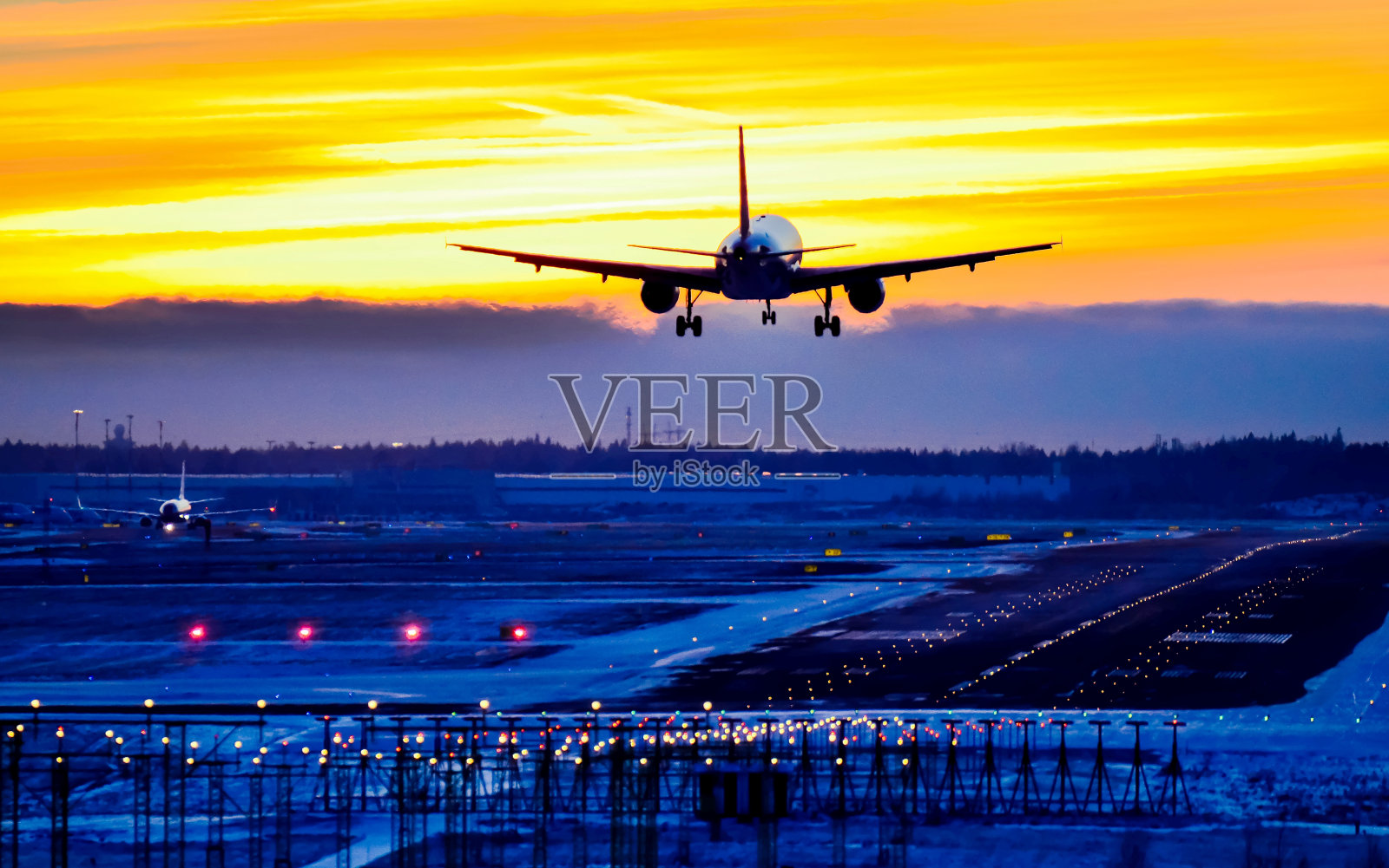 飞机在日落时降落在机场跑道上照片摄影图片