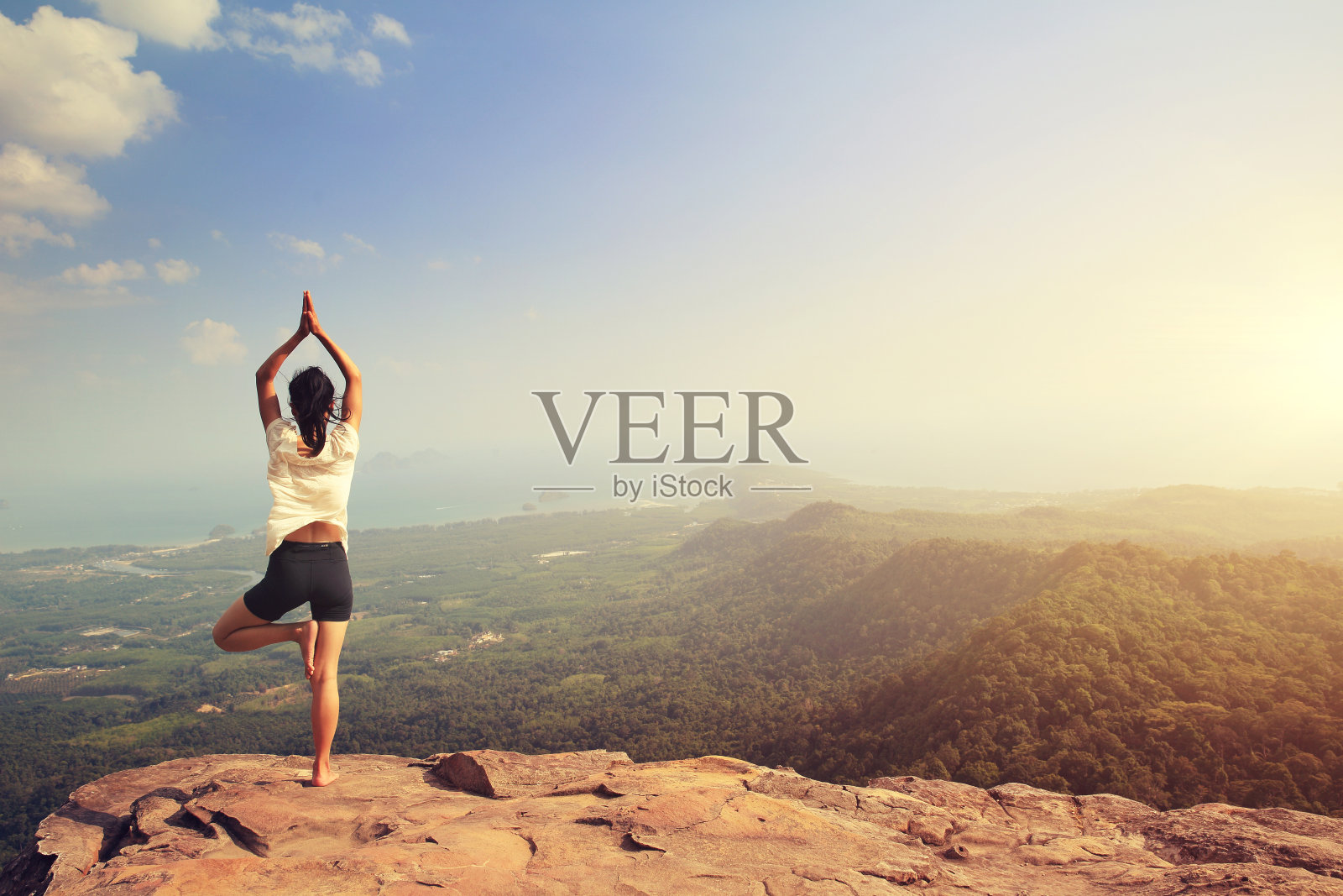 一名年轻的健身女性在山峰峭壁上练习瑜伽照片摄影图片