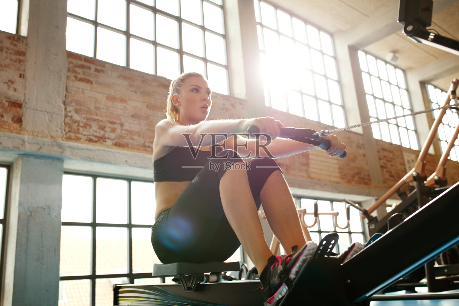 年轻女子在健身机上做运动照片摄影图片