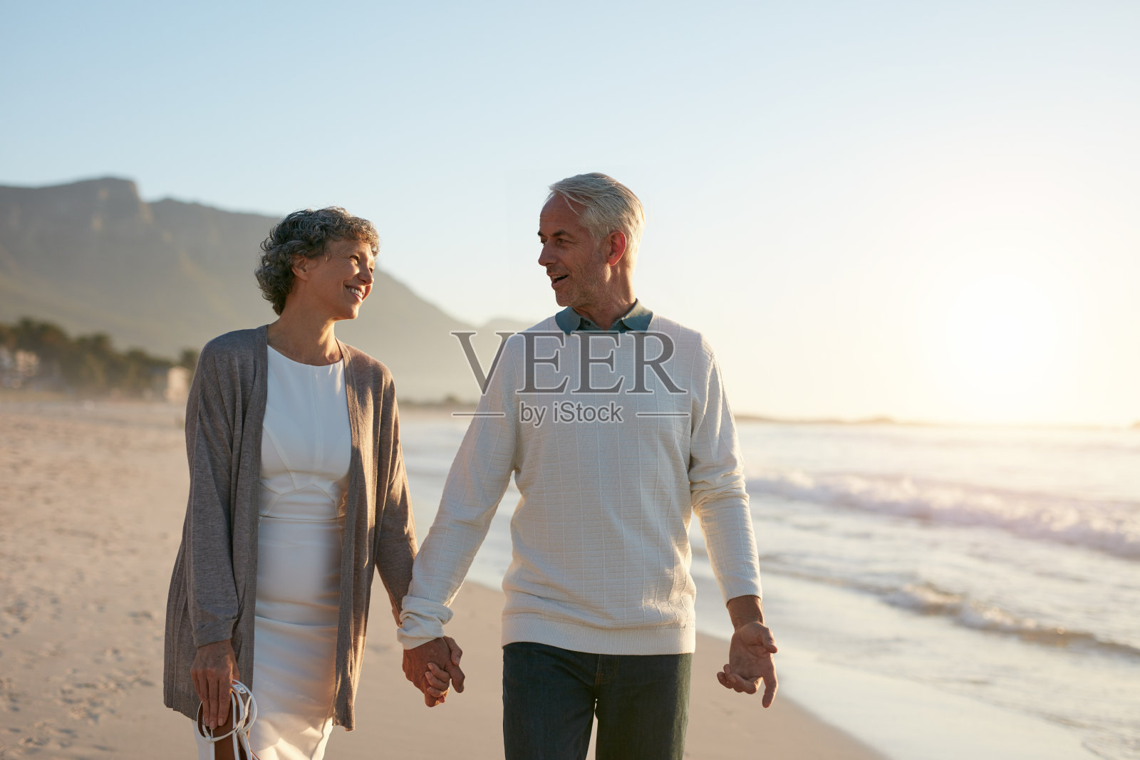 一对相爱的老年情侣在海滩上散步照片摄影图片