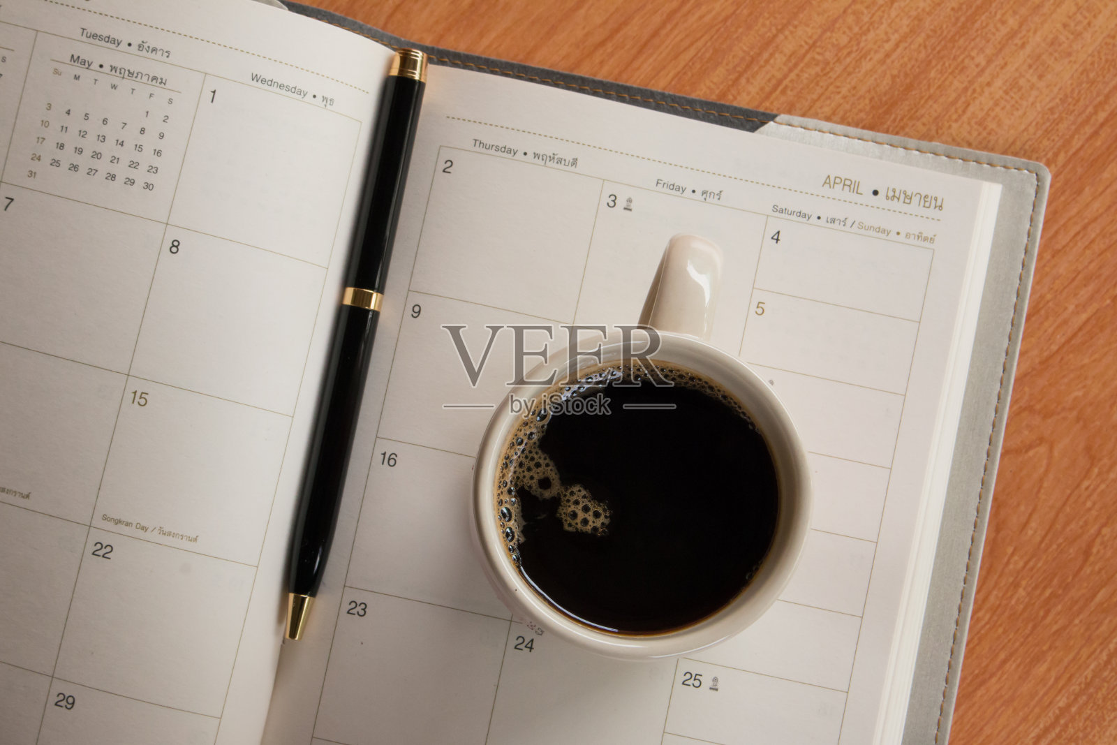 一杯咖啡和一支笔，放在带有日历计划的笔记本上照片摄影图片