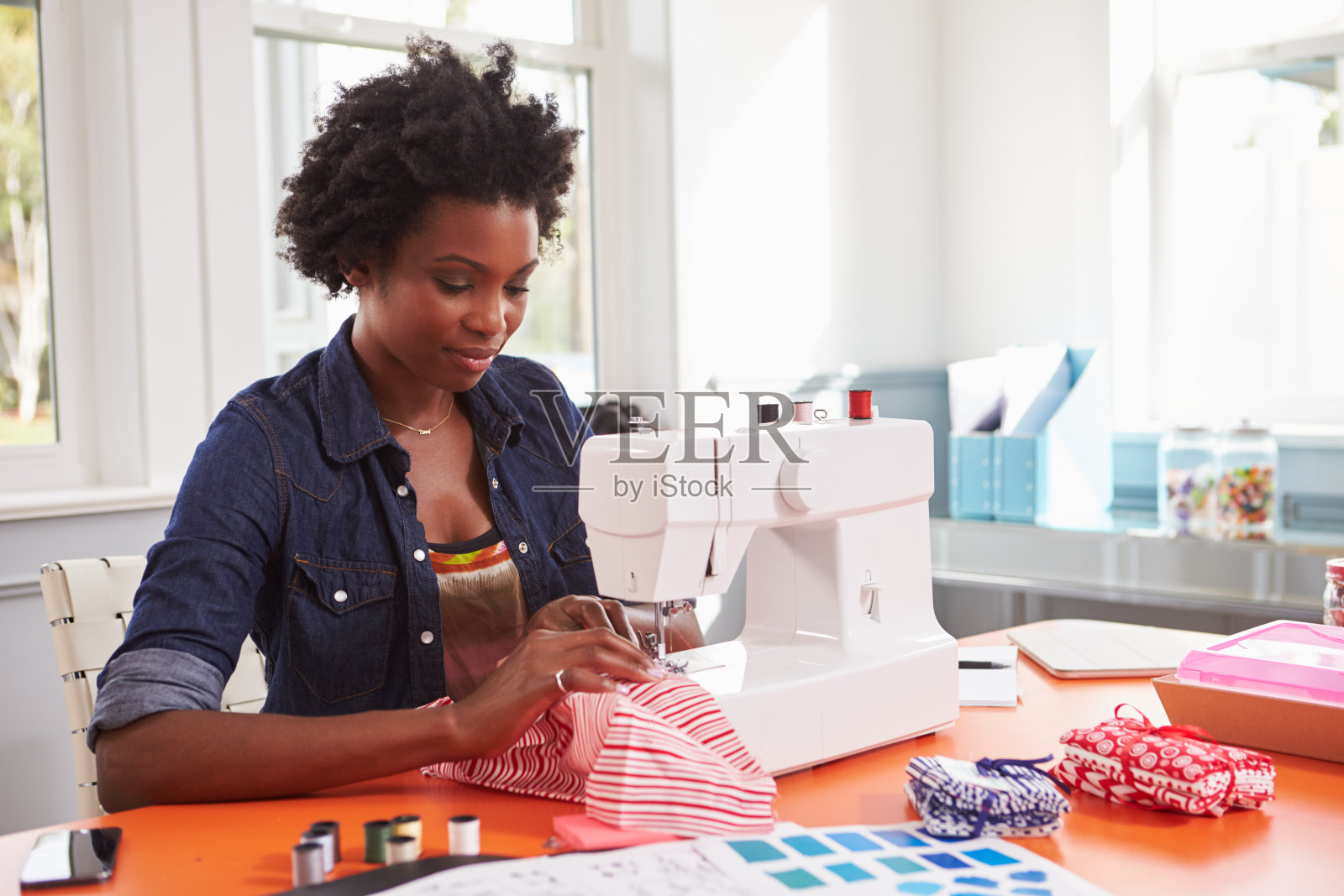 用缝纫机缝制布料的年轻黑人妇女照片摄影图片