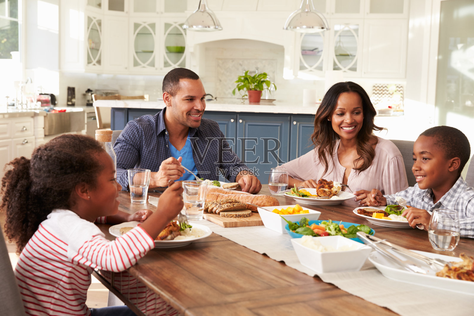 父母和他们的两个孩子在餐桌上吃饭照片摄影图片